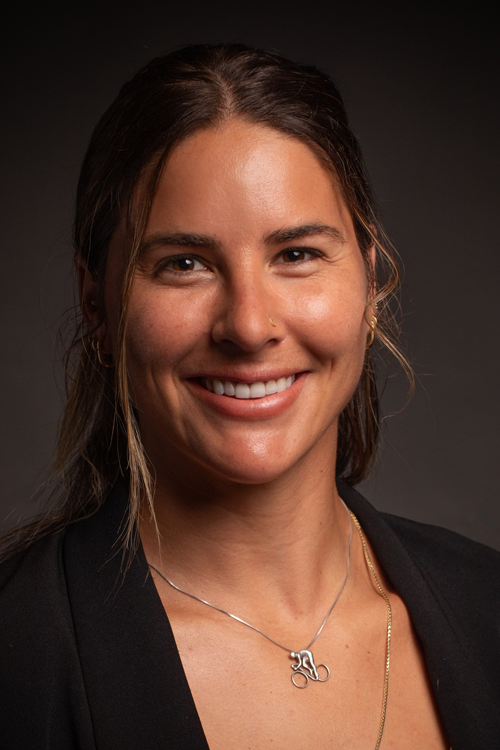 Woman with long brown hair looks at camera and smiles. 